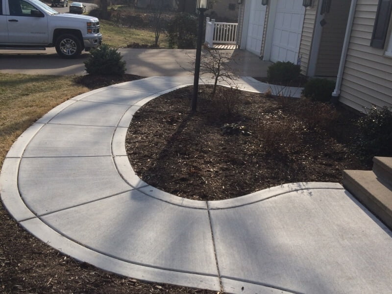 Concrete sidewalk of a house in a round shape connecting driveway with entrance